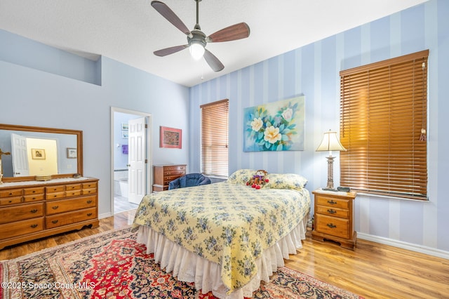 bedroom with ceiling fan, connected bathroom, a textured ceiling, and light wood-type flooring