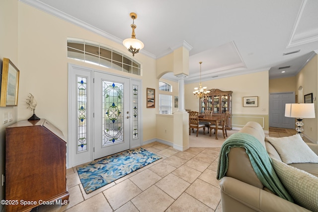 foyer featuring crown molding, light tile patterned floors, an inviting chandelier, and ornate columns