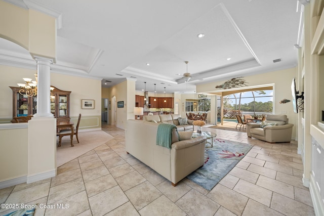 tiled living room with crown molding, a tray ceiling, ceiling fan, and ornate columns