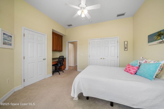 bedroom with ceiling fan, built in desk, a closet, and light carpet