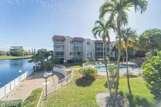 view of property's community featuring a yard, a swimming pool, and a water view