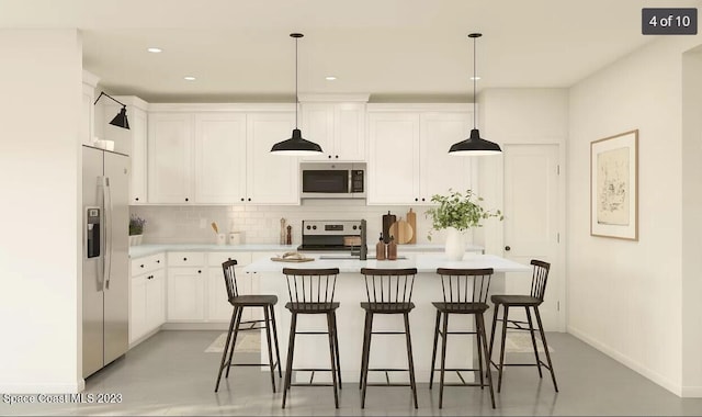 kitchen featuring white cabinetry, appliances with stainless steel finishes, a breakfast bar, and hanging light fixtures