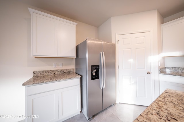 kitchen featuring white cabinetry, stainless steel refrigerator with ice dispenser, light stone countertops, and light tile patterned flooring