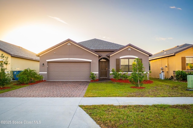 single story home featuring a garage and a yard