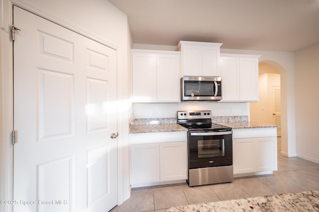 kitchen featuring white cabinetry, appliances with stainless steel finishes, light tile patterned flooring, and light stone counters