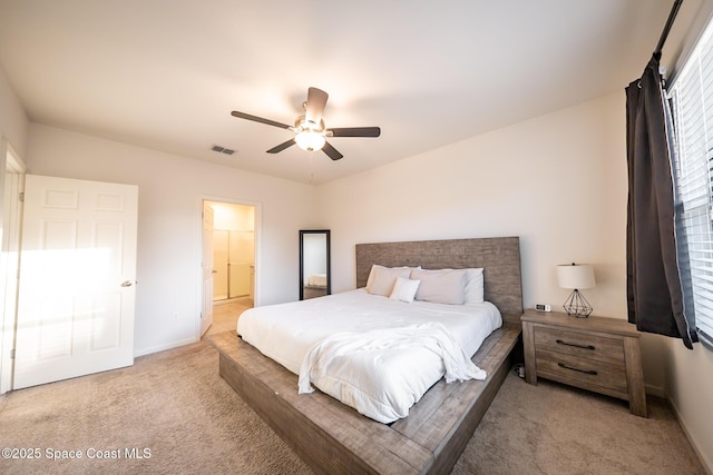 bedroom featuring light carpet, ensuite bath, and ceiling fan