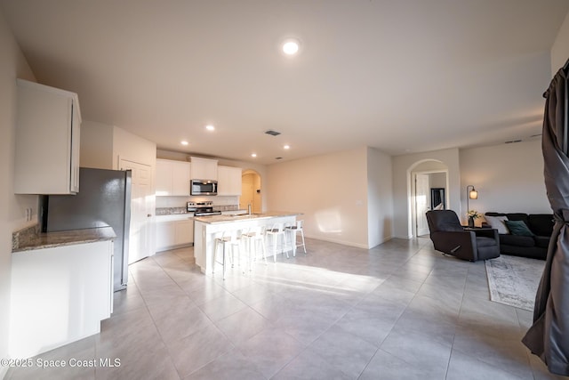 kitchen featuring a kitchen bar, sink, white cabinetry, a center island with sink, and appliances with stainless steel finishes