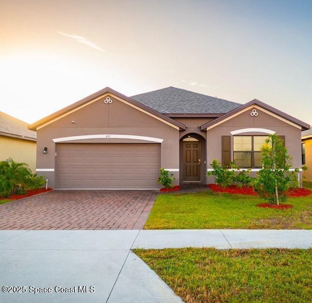 ranch-style house with a garage and a yard