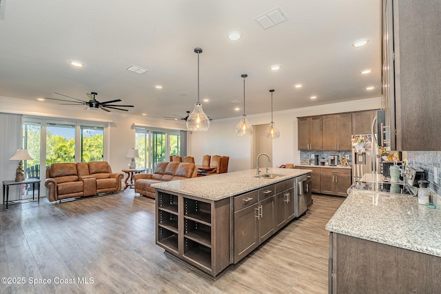 kitchen with sink, hanging light fixtures, a kitchen island with sink, light stone countertops, and high end fridge