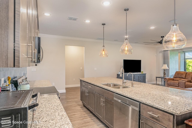 kitchen featuring an island with sink, sink, stainless steel appliances, crown molding, and light stone countertops