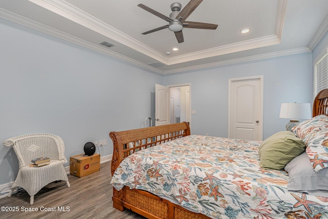 bedroom with ceiling fan, ornamental molding, a raised ceiling, and light hardwood / wood-style floors