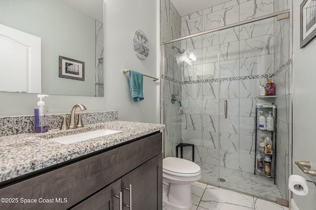 bathroom with vanity, a shower with door, and toilet