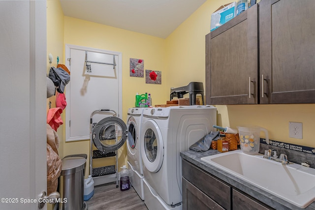 laundry room with cabinets, wood-type flooring, sink, and washing machine and dryer