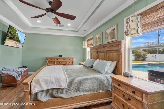 bedroom featuring hardwood / wood-style flooring, ornamental molding, a raised ceiling, and ceiling fan