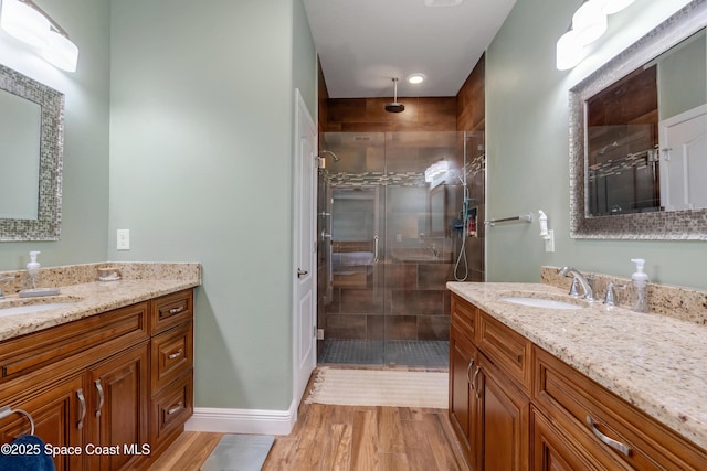 bathroom with wood-type flooring, vanity, and a shower with shower door