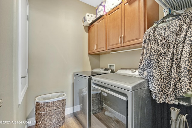 laundry room featuring cabinets, washing machine and clothes dryer, and light hardwood / wood-style flooring