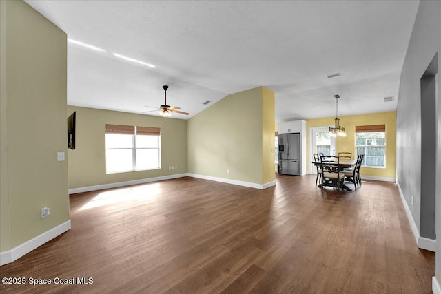 unfurnished living room with lofted ceiling, hardwood / wood-style floors, and ceiling fan with notable chandelier