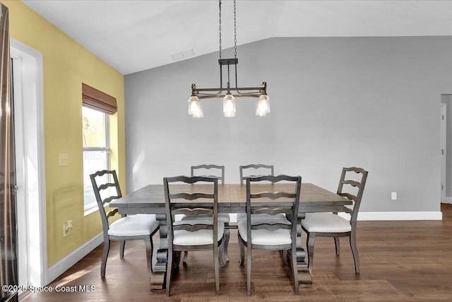 dining room featuring dark wood-type flooring, lofted ceiling, and a notable chandelier