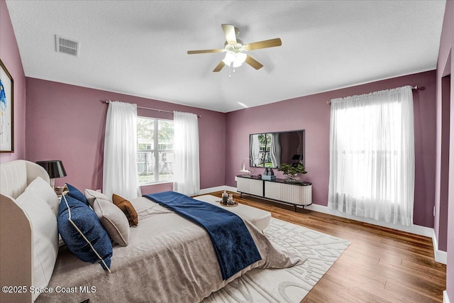 bedroom with wood-type flooring, a textured ceiling, and ceiling fan