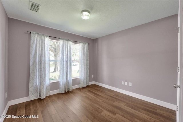 spare room with wood-type flooring and a textured ceiling