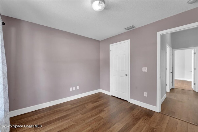 unfurnished bedroom featuring dark hardwood / wood-style floors and a textured ceiling