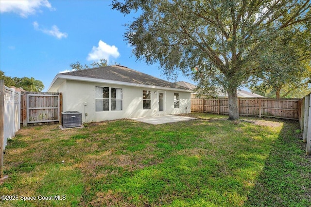 rear view of property featuring a yard, central AC unit, and a patio area