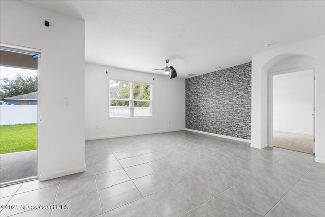 tiled empty room featuring a textured ceiling and ceiling fan