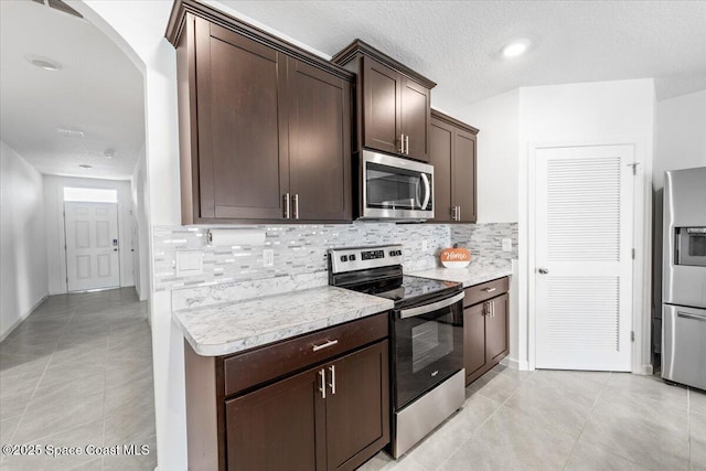 kitchen with decorative backsplash, light countertops, appliances with stainless steel finishes, and dark brown cabinetry