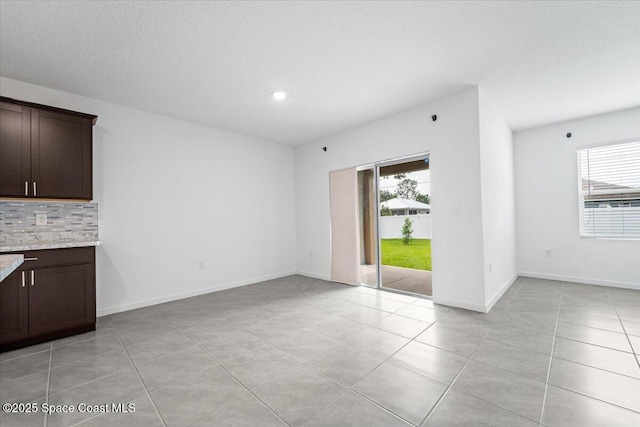 interior space featuring light tile patterned floors, baseboards, and a textured ceiling