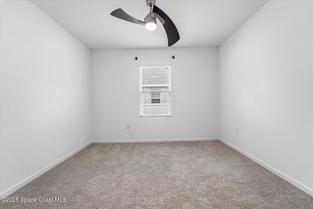 carpeted spare room featuring baseboards, a textured ceiling, and ceiling fan