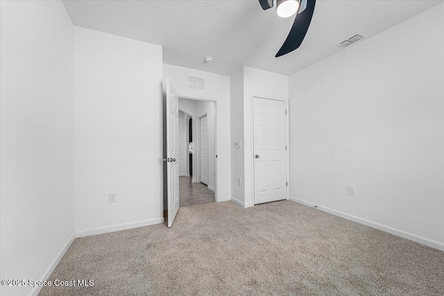 unfurnished bedroom with visible vents, a textured ceiling, baseboards, and carpet