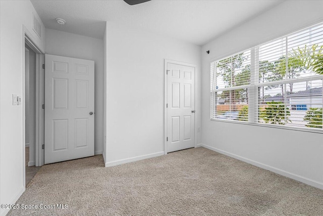 unfurnished bedroom featuring carpet flooring, visible vents, and baseboards