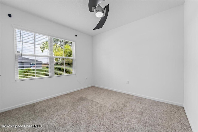 carpeted spare room with a ceiling fan and baseboards