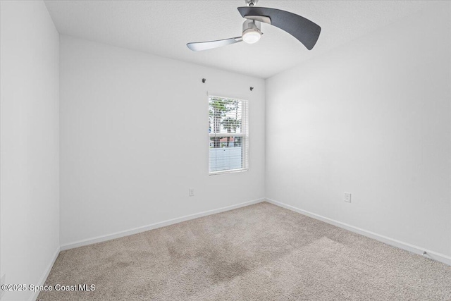 carpeted spare room featuring baseboards and a ceiling fan