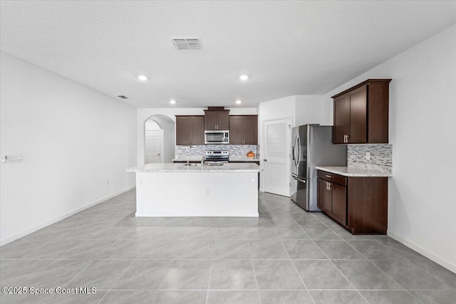 kitchen featuring arched walkways, visible vents, dark brown cabinets, and stainless steel appliances