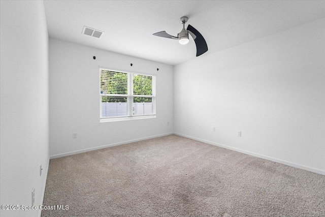 carpeted spare room with visible vents, baseboards, and ceiling fan