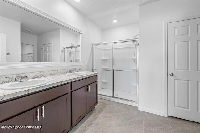 full bathroom with tile patterned floors, a stall shower, double vanity, and a sink