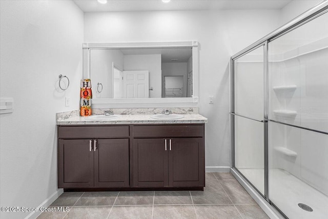 bathroom with double vanity, a shower stall, and a sink