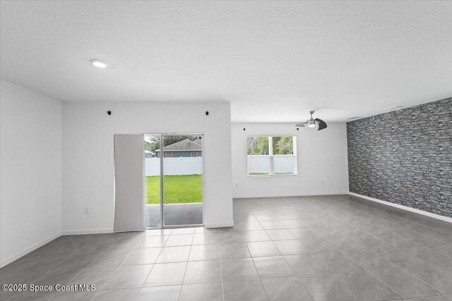 tiled spare room featuring baseboards and a textured ceiling