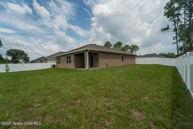 back of property with a fenced backyard, a lawn, and stucco siding