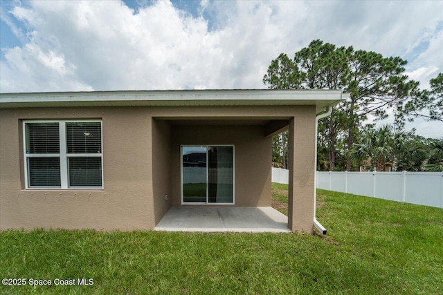 back of house with stucco siding, a patio, a lawn, and fence