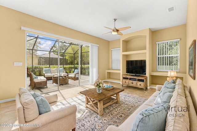 living room with built in shelves and ceiling fan