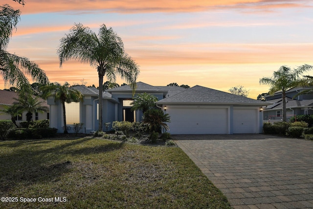 view of front of property with a garage and a lawn