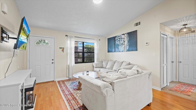 living room with lofted ceiling, wood-type flooring, and a textured ceiling