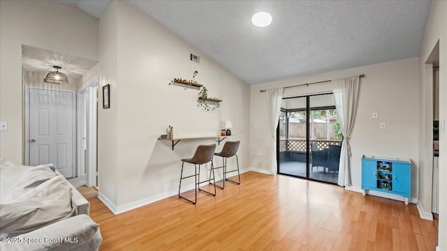 interior space with hardwood / wood-style flooring, vaulted ceiling, and a textured ceiling