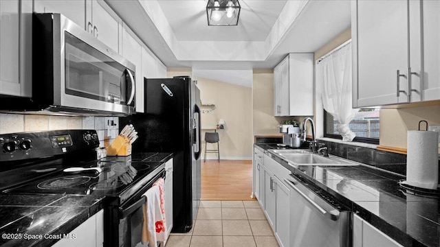 kitchen featuring sink, white cabinetry, backsplash, stainless steel appliances, and light tile patterned flooring