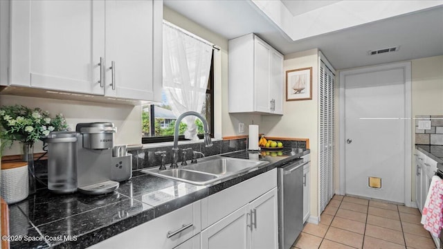 kitchen featuring white cabinetry, stainless steel dishwasher, sink, and light tile patterned floors