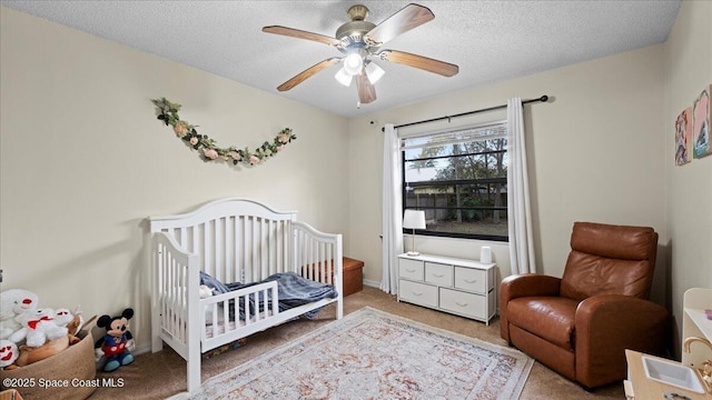 bedroom featuring ceiling fan, carpet floors, a nursery area, and a textured ceiling