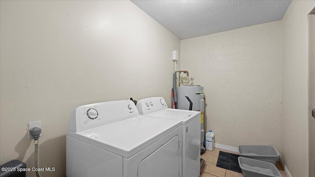 laundry area featuring light tile patterned flooring, washing machine and dryer, water heater, and a textured ceiling