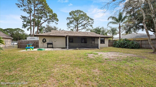 rear view of property featuring a sunroom, a yard, and a patio area